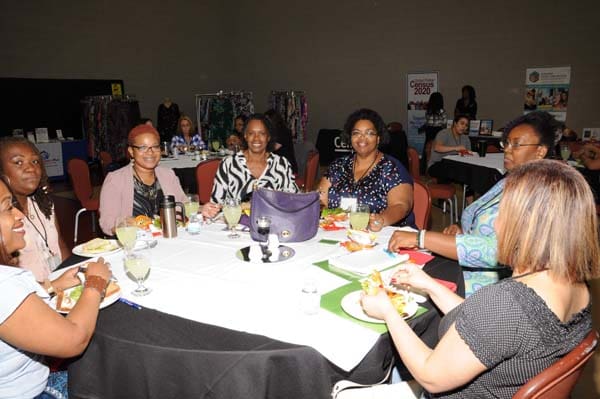 A group of five women seated around a table at a social event.