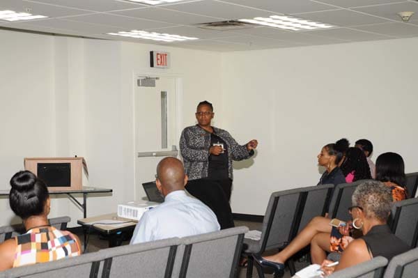 A woman presenting to an attentive audience in a conference room.