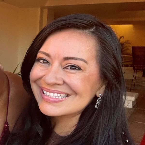 Smiling woman with long dark hair indoors.