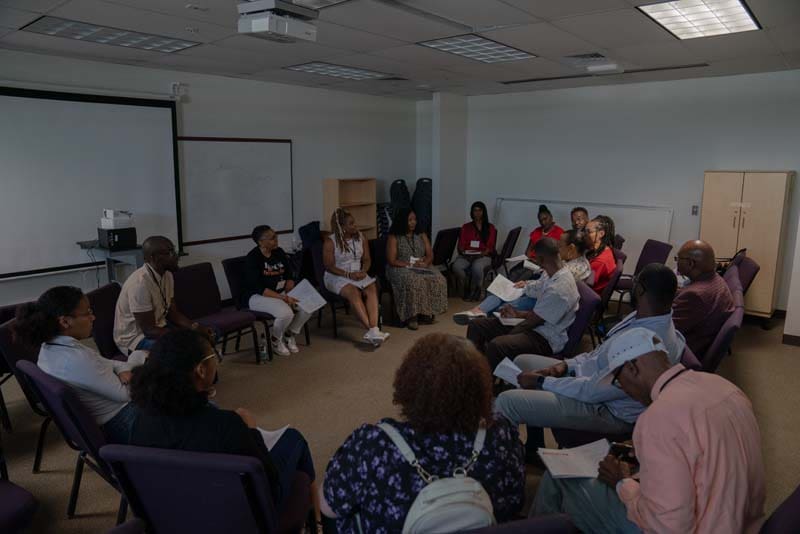 A group discussion in a classroom setting with participants seated in a circle.