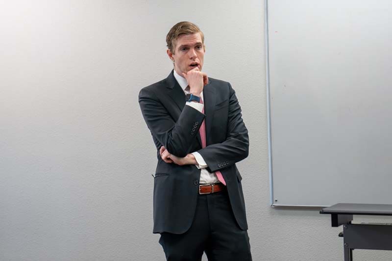Thoughtful businessman standing with hand on chin in office.