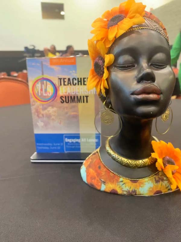 Decorative African-style bust with orange flowers at a teacher summit.