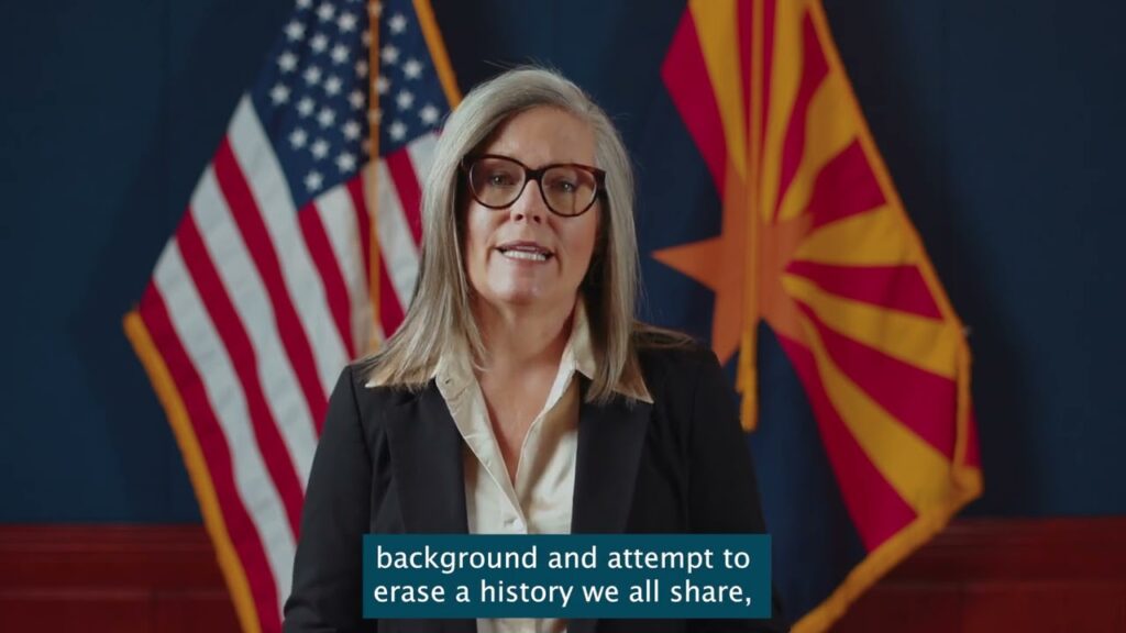 Woman speaking with American and Arizona flags.