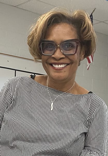 Smiling woman with glasses in checkered top.
