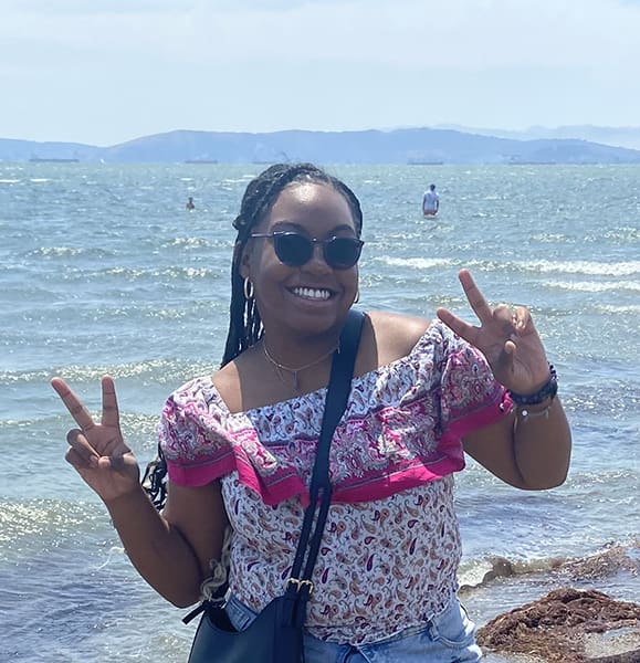 Woman smiling by the sea, peace signs.