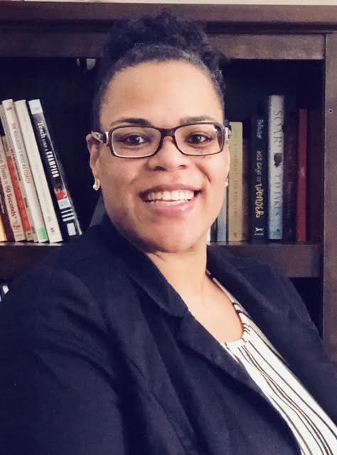 Smiling person in front of a bookshelf.