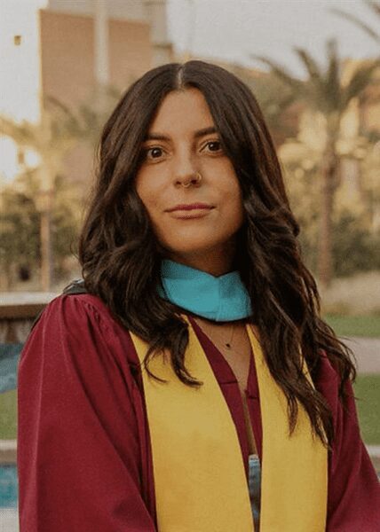 Young woman in graduation attire outdoors.