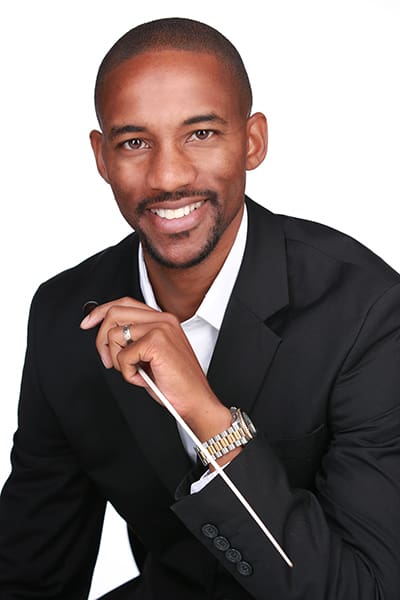 Man in suit holding a conductor's baton.