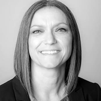 Smiling woman with straight hair, black blazer.