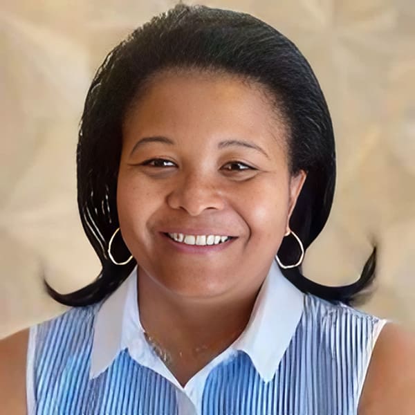 Smiling woman with hoop earrings, white top.