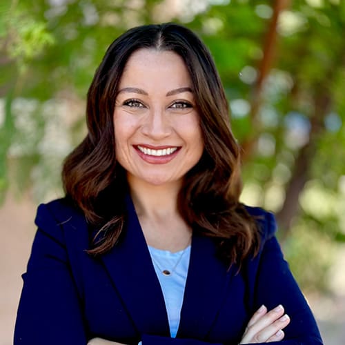 Smiling woman in blue blazer outdoors.