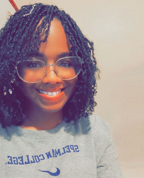 Smiling person with glasses and curly hair.