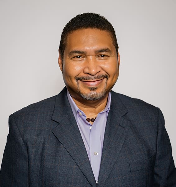 Smiling man in a dark suit jacket.