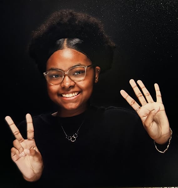 Person smiling, showing peace and four fingers.