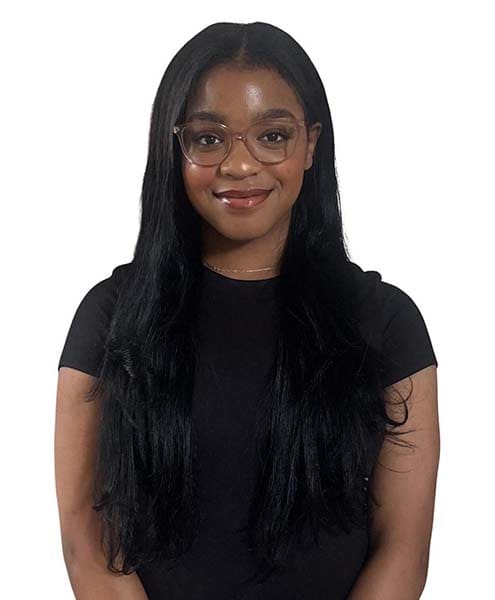 Person with long hair and glasses smiling.