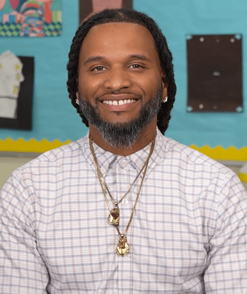 Smiling man with beard and braids.