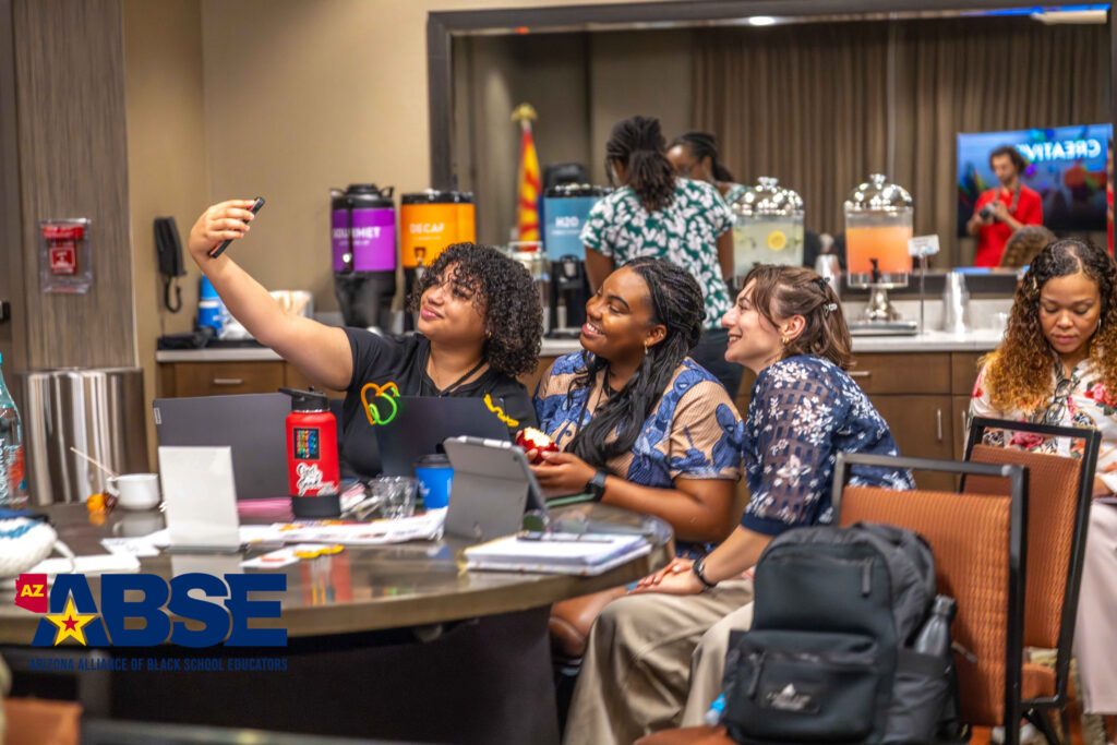 Three women joyfully taking a selfie at a vibrant event booth.