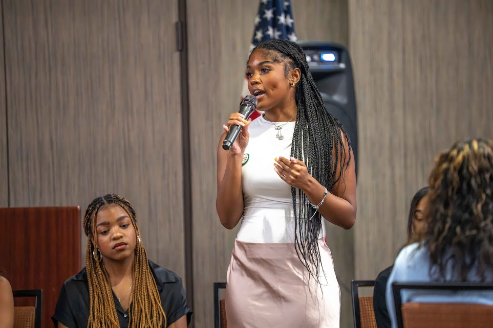 A woman speaks into a microphone while another listens attentively.
