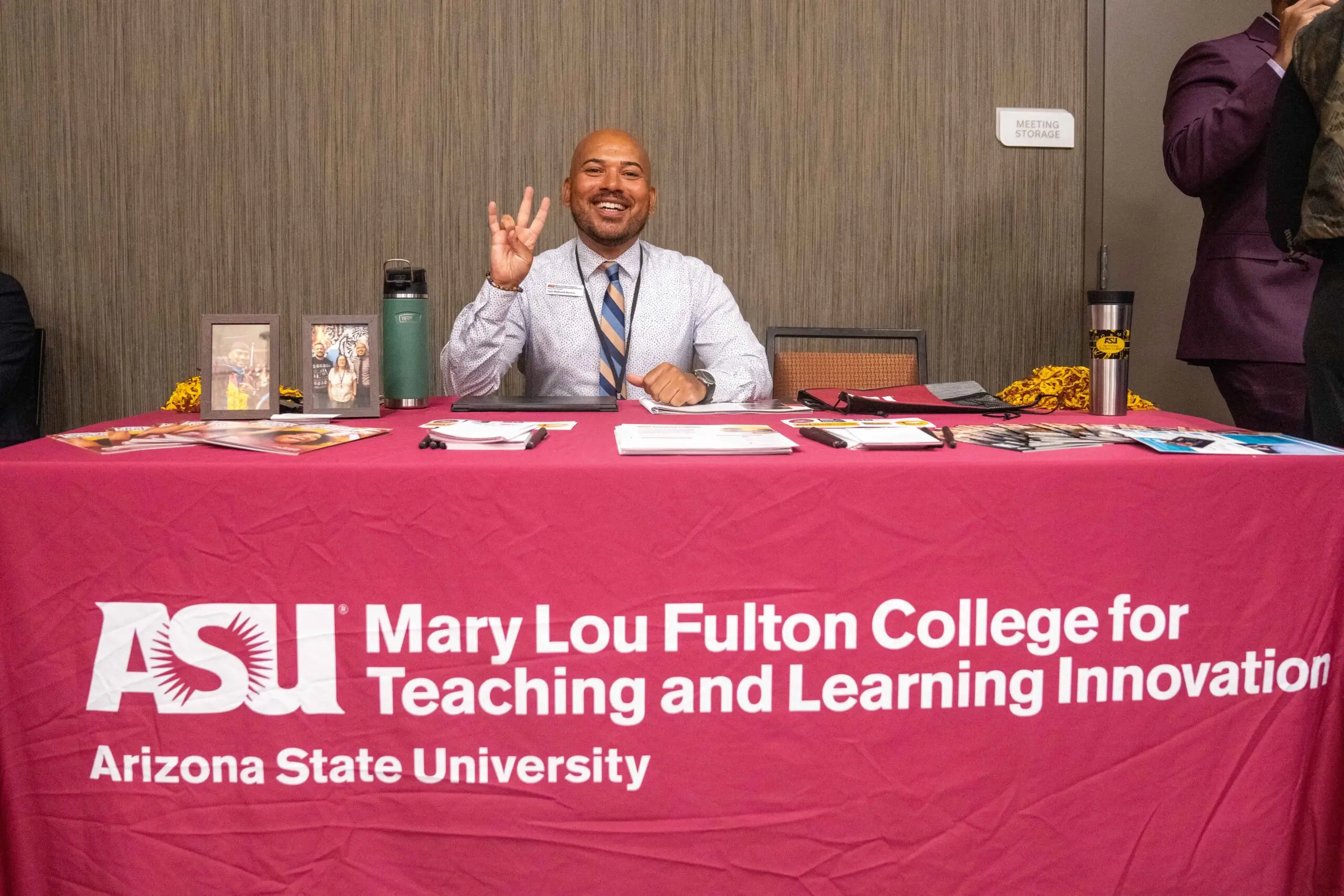 Man at ASU information table, smiling.