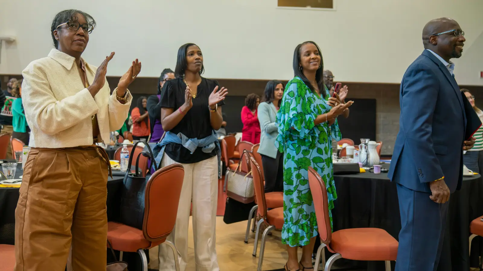 People standing and clapping at an event.